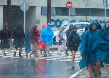 Peregrinos que se encuentran en la última etapa del Camino Francés se protegen este martes de la lluvia. (EFE/Xoán Rey)