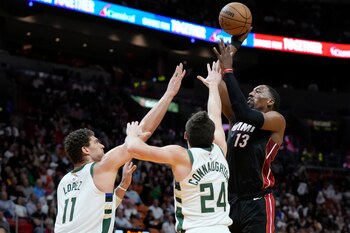 Bam Adebayo, pívot del Heat de Miami, dispara ante Brook López y Pat Connaughton, de los Bucks de Milwaukee, el jueves 12 de enero de 2023 (AP Foto/Wilfredo Lee)