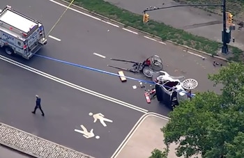 Vista aérea de un carruaje volcado en una carretera mojada de Central Park, con un camión de policía y cinta de seguridad en la escena
