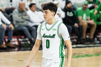 Un jugador de baloncesto con camiseta blanca número cero camina por la cancha frente al público en las tribunas
