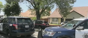 Patrullas del Departamento de Policía de San José estacionadas en una calle residencial frente a una casa con garaje y árboles