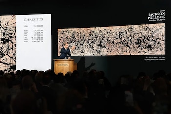 Subasta de arte con un cuadro de Jackson Pollock en pantalla gigante, mostrando un precio de 157 millones de dólares y un subastador en el podio