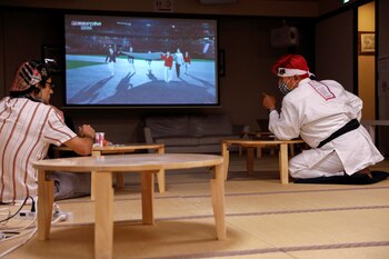 Kazunori Takishima, dressed in an aikido uniform, watches the Tokyo 2020 Olympics closing ceremony together with customers, at his guest house in Tokyo, Japan August 8, 2021. REUTERS/Androniki Christodoulou