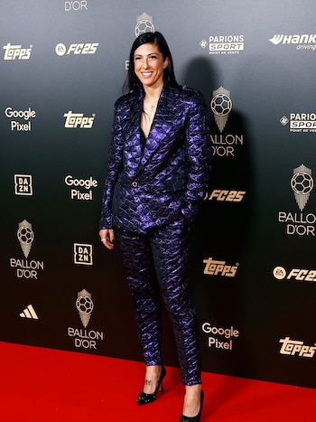 Jennifer Hermoso, futbolista española, resaltó con un traje de dos piezas de diseño único en tejido acolchado y en un vibrante tono púrpura metálico, lo que le da un aspecto moderno y llamativo. Sus zapatos de tacón negros que añaden un toque de elegancia al conjunto. (REUTERS/Sarah Meyssonnier)