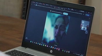 Pantalla de laptop mostrando una videollamada; en el encuadre principal, una mujer con expresión preocupada; en uno pequeño, dos hombres