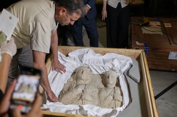 A museum employee opens a crate containing Palmyrene funerary reliefs that once adorned the walls of tombs and date to the second and third centuries A.D. after Syrian authorities unveiled antiquities returned from France at the National Museum in Damascus, Syria, Wednesday, July 8, 2026.(AP Photo/Ghaith Alsayed) ADDITION: Adds identification of the artifact as Palmyrene funerary reliefs.