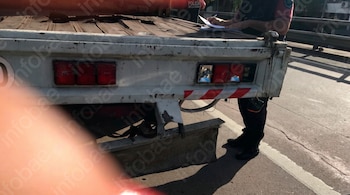La parte trasera de un camión blanco estacionado y un oficial de policía que escribe sobre una hoja de papel.