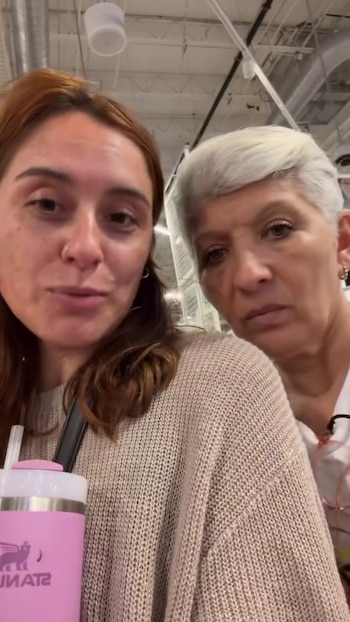 Una mujer con suéter marrón sostiene un vaso rosado con sorbete junto a una mujer de cabello corto blanco
