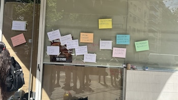 Vitrina de vidrio con varios carteles de papel de colores y notas manuscritas pegadas con cinta