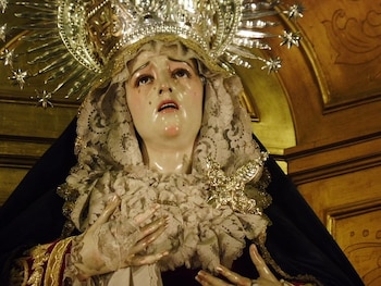 La Dolorosa se representa con túnicas negras o moradas, colores asociados al luto y a la penitencia durante la Cuaresma.El corazón atravesado por siete espadas representa los dolores de María vinculados a la pasión de Cristo, según la devoción difundida desde el siglo XIII. El rosario de los Siete Dolores es una forma de oración que recuerda momentos clave del sufrimiento de María, mantenida por comunidades y cofradías