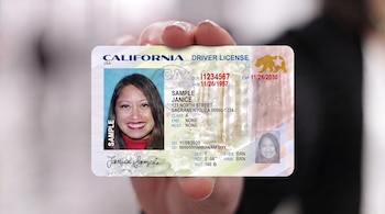 Una mano sostiene una licencia de conducir de California con una fotografía de mujer, datos de Janice Sample y el código J66S en la tarjeta.