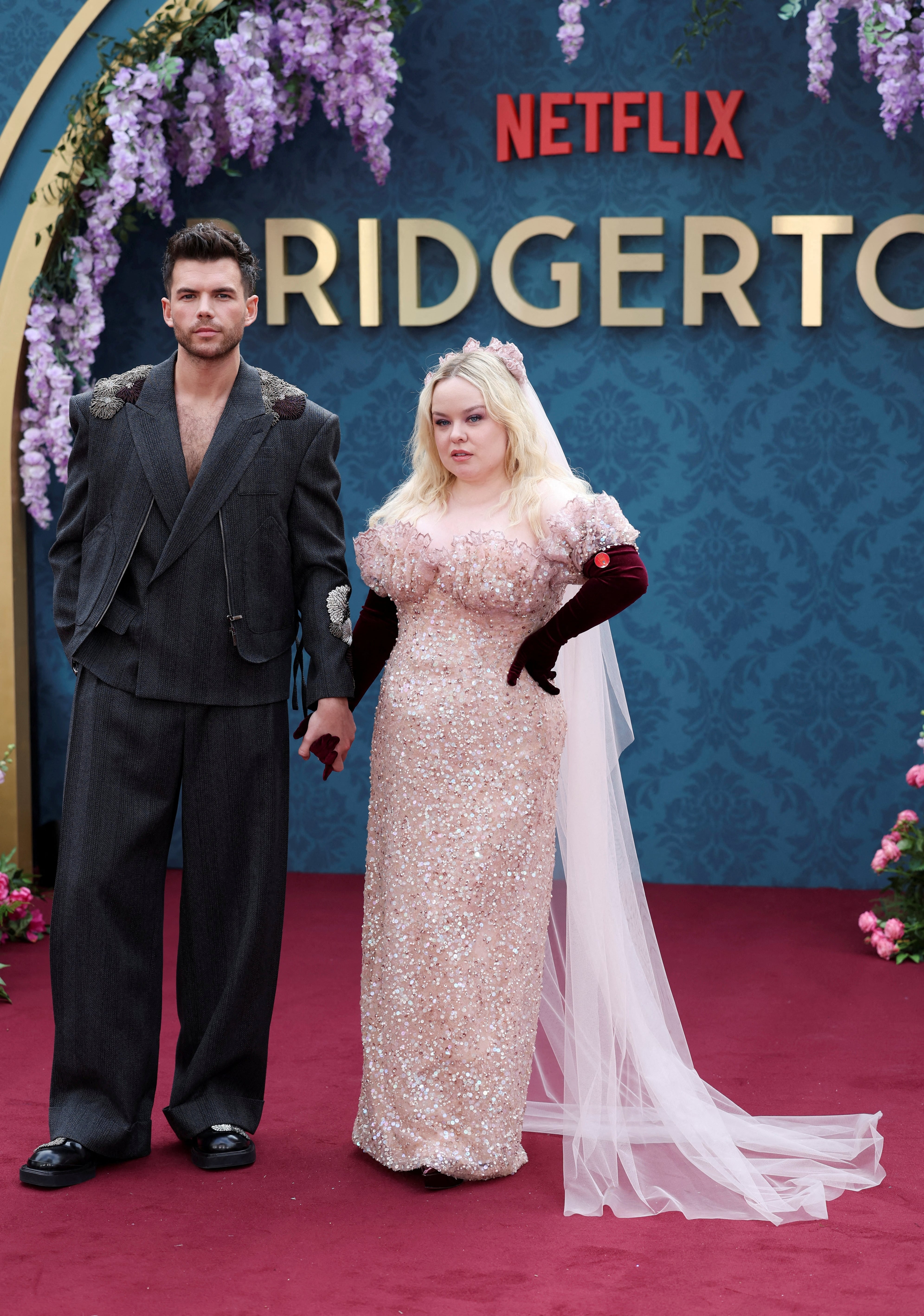 Luke Newton moderniza el traje clásico con una chaqueta amplia bordada y pantalones anchos en tono gris oscuro (REUTERS)