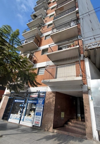 Edificio de departamentos con fachada de ladrillo, balcones, un local comercial en la planta baja y una entrada con escalones