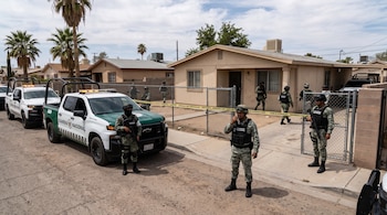 Agentes armados con uniformes militares y camionetas de la Guardia Nacional permanecen frente a una casa delimitada con cinta de seguridad.