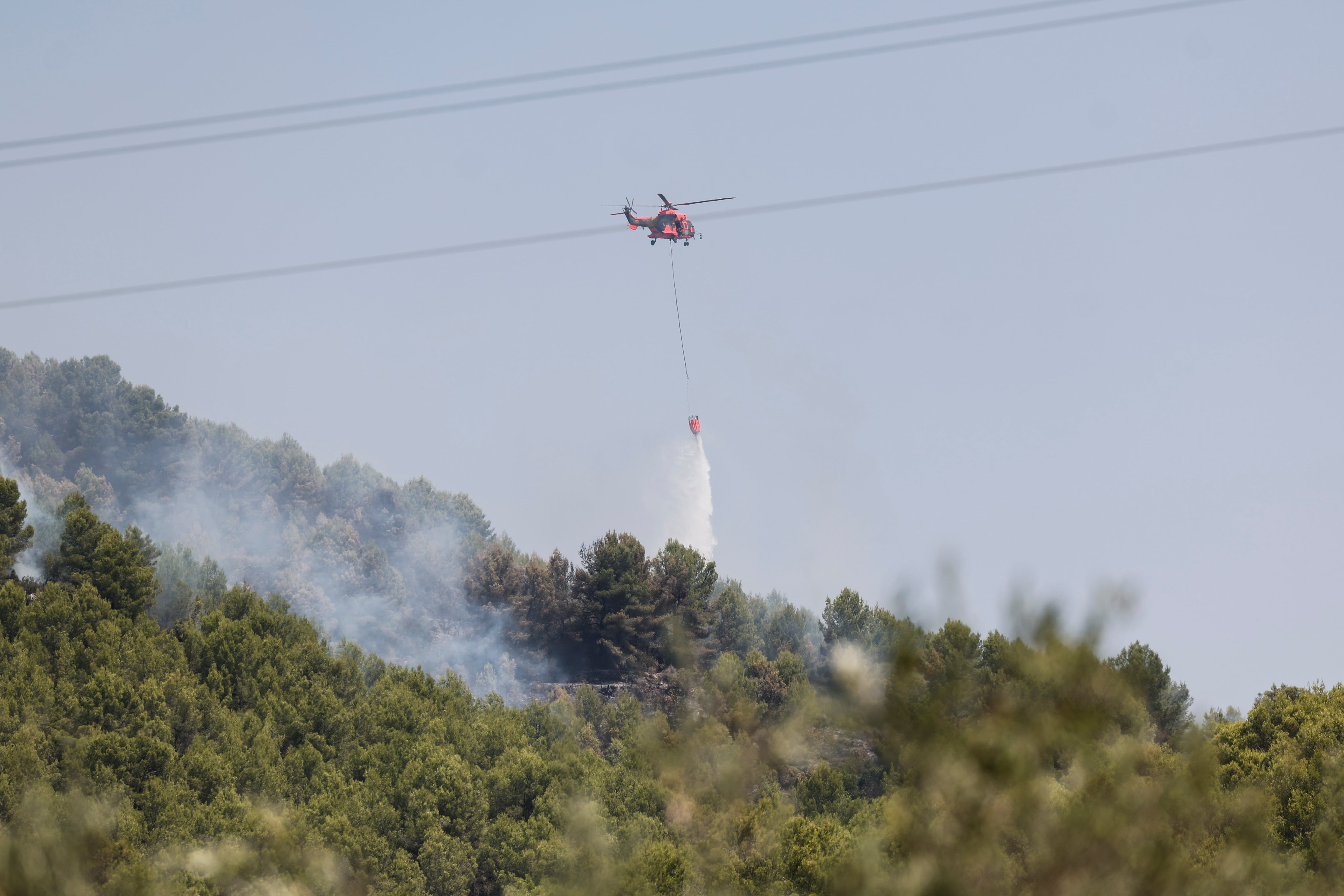 Un helicóptero descarga agua en los alrededores de Artana (Castellón), uno de los municipios afectados por el incendio declarado el pasado sábado en la Vall d