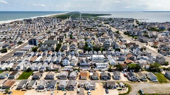 Vista aérea de un asentamiento costero densamente poblado con cientos de casas, calles, y masas de agua oceánica y de bahía bajo un cielo azul claro