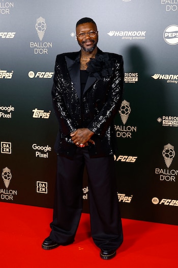 El exjugador francés Djibril Cisse llevó una chaqueta de esmoquin negra con lentejuelas que le da un toque brillante y llamativo. La prenda incluyó un adorno de gran flor negra en el lado izquierdo del pecho, añadiendo un elemento audaz y creativo al conjunto. El conjunto refleja un estilo distintivo y audaz, resaltando en la atmósfera sofisticada del evento. (REUTERS/Sarah Meyssonnier)