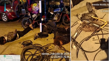 Tres personas yacen en el suelo rodeadas de cables y herramientas. Al fondo se observa un automóvil rojo, una bicicleta y una motocicleta, con texto de fecha y coordenadas