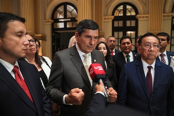 El presidente del Consejo de Ministros, Luis Arroyo Sánchez, habla a un micrófono rojo con logo "tvpe". Viste traje oscuro y corbata, con el puño ligeramente cerrado. Otros funcionarios lo rodean en un salón