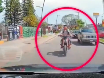 Un automóvil de plataforma digital circula por una avenida del centro de Chapala, Jalisco, seguido de cerca por varias motocicletas y un auto gris. Crédito: Especial
