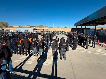 Decenas de efectivos policiales uniformados formados en una explanada junto al cartel del Paso Internacional La Quiaca-Villazón