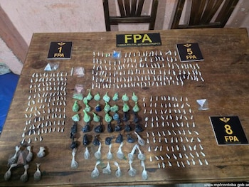 Cientos de pequeños envoltorios con sustancia, bolsas plásticas y carteles con el texto FPA están ordenados sobre una mesa de madera