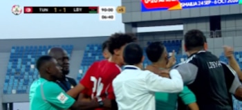 Varios futbolistas e integrantes del equipo técnico de Libia se agrupan y discuten cerca del campo de juego