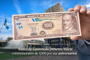 Una mano sostiene un billete conmemorativo de Q100 frente al edificio del Banco de Guatemala y una bandera nacional bajo un cielo azul.
