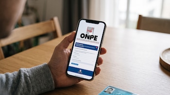 Una mano sostiene un teléfono inteligente que muestra la página web de la ONPE, junto a un documento de identidad peruano sobre una mesa.