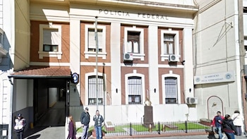 Fachada de un edificio de ladrillo y hormigón con la inscripción Policía Federal, ventanas con rejas y personas caminando por la vereda