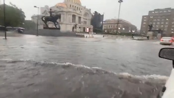 Vista a nivel de calle de una avenida severamente inundada en la Ciudad de México, con el Palacio de Bellas Artes y la escultura del Caballito al fondo