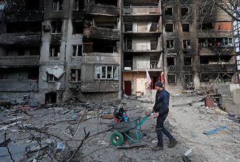 A local resident pushes a wheelbarrow in front of an apartment building destroyed during Ukraine-Russia conflict in the besieged southern port city of Mariupol, Ukraine March 30, 2022. REUTERS/Alexander Ermochenko