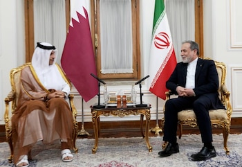 Dos representantes oficiales sentados en sillones junto a las banderas de Qatar e Irán frente a una mesa con micrófonos