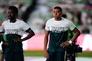 Dos futbolistas en un estadio de fútbol vistiendo camisetas blancas con la frase impresa TODOS SOMOS CABALLAS y el dibujo de un pez