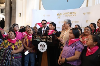 Una mujer habla ante un atril del Congreso de la República rodeada de personas con pañuelos de color rosa al cuello