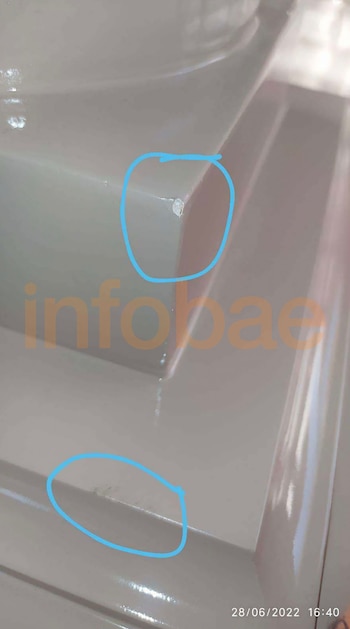 Primer plano del borde de un mueble beige con pequeñas marcas en la pintura señaladas por dos círculos azules
