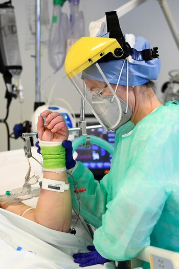 Una enfermera en Bergamo sostiene la mano de un paciente grave con COVID-19 - REUTERS/Flavio Lo Scalzo