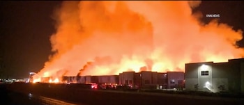 Un edificio industrial arde durante la noche con intensas llamas de color naranja y una densa nube de humo