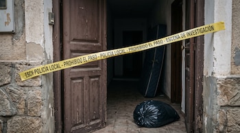 Entrada de una vivienda acordonada con cinta amarilla de la Policía Local, con una bolsa negra y un colchón en el suelo del interior.