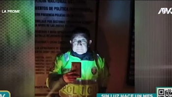 Policía alumbra con su celular para poder atender a un ciudadano.