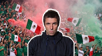 Hombre de mediana edad con chaqueta oscura y cabello oscuro sobre un fondo de estadio con aficionados, banderas de México y humo rojo y verde.
