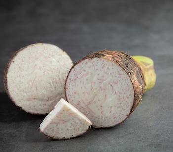A raiz do taro foi cortada e dividida na área escura, mostrando o interior branco com veias e pontos roxos.