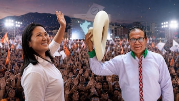 Keiko Fujimori y Roberto Sánchez sonríen y saludan a una multitud en un mitin político al aire libre. Confeti cae mientras un mapa de Perú se ve en el fondo