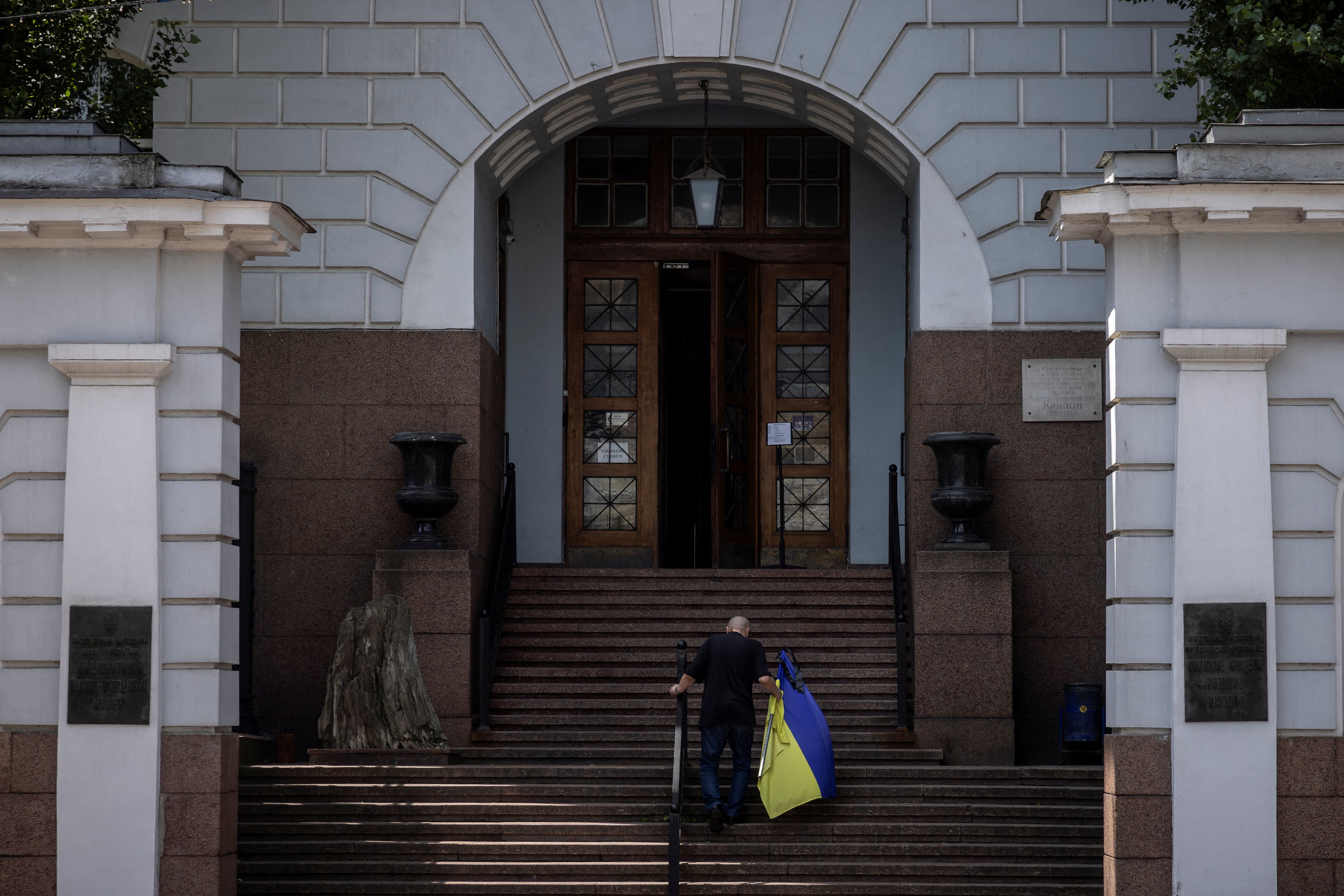 Un hombre lleva una bandera ucraniana al museo tras ataques rusos. Más de 1,680 sitios culturales han sido dañados durante la guerra (REUTERS/Thomas Peter)