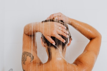Una mujer de espaldas lavandose el pelo en la ducha (Pexels)