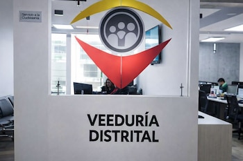Oficina con texto Veeduría Distrital, logo de un ojo amarillo y rojo con símbolo de personas, y letrero Servicio a la Ciudadanía.
