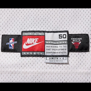Primer plano de etiquetas de tela en una camiseta deportiva blanca con logos de la NBA Authentics, Nike y Chicago Bulls, número 50 y texto de autenticidad