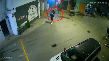 Grabación de cámara de seguridad nocturna mostrando dos figuras en una calle de Villa 31, con un vehículo blanco en primer plano y edificios a los lados