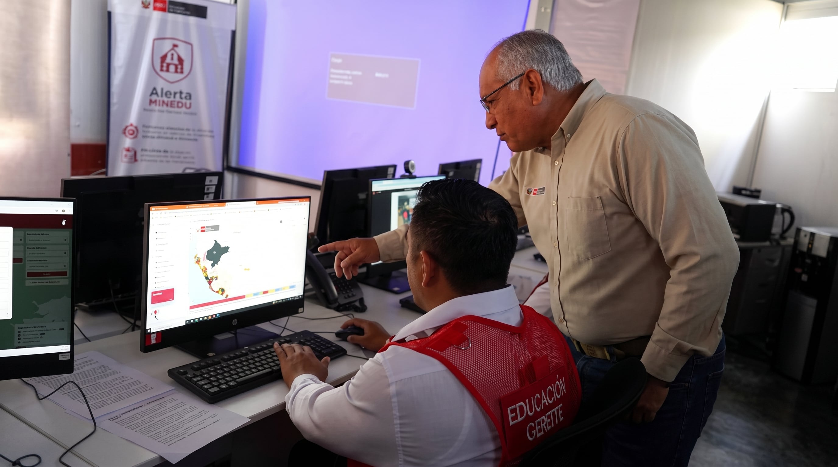 Un operador y un supervisor del Ministerio de Educación del Perú analizan datos sobre un mapa interactivo en la plataforma Alerta MINEDU. (Imagen Ilustrativa Infobae)