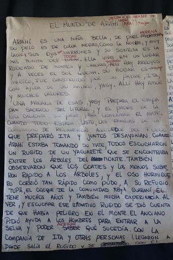 Hoja de papel con un texto manuscrito en letras mayúsculas que presenta tachaduras y notas de corrección en tinta roja